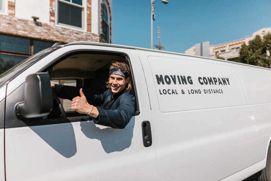 Three individuals are preparing for a home relocation, sitting inside the open rear of a white moving van. The van's interior shows various packing materials, including cardboard boxes of different si